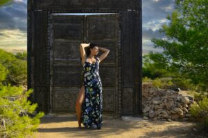 Woman in dress stands by rustic wooden structure